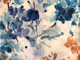 Slightly velvety white upholstery fabric printed with watercolour style abstract floral designs in the colourway Blues (navy, indigo, blue teal, taupe, and dark brown)
