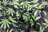 Swirled swatch of marijuana leaf printed fabric in black (black fabric with tiled grey and green pot leaves tossed)