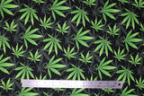 Flat swatch of marijuana leaf printed fabric in black (black fabric with tiled grey and green pot leaves tossed)