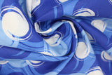 Swirled swatch blotches printed fabric in blue (medium blue fabric with light blue, dark blue, and white coloured circular blotches collage)