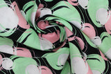Swirled swatch blotches printed fabric in black (black fabric with light pink, light green, and white coloured circular blotches collage)