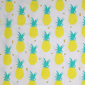 Swatch of pineapple print fabric on white (tiled yellow and green pineapples with tossed tiny gold hearts)