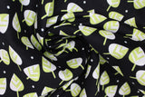 Swirled swatch small leaves printed fabric in black (black fabric with tossed cartoon white/green leaves and small occasional white polka dots)