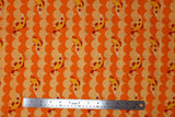 Flat swatch cartoon fish and scales printed fabric in orange (light and dark orange alternating horizontal scale/scalloped pattern with tossed orange coy style fish)