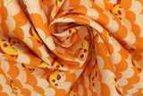 Swirled swatch cartoon fish and scales printed fabric in orange (light and dark orange alternating horizontal scale/scalloped pattern with tossed orange coy style fish)
