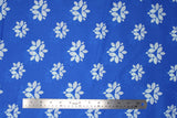 Flat swatch of blue fabric in lotus (bright blue fabric with white lotus shapes in medium and large sizes tiled)