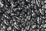 Swirled swatch of mountain cabins printed fabric in black (black fabric with tossed white cartoon mountains and cabin print repeated)