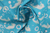 Swirled swatch of sea life fabric in seahorses (blue) (bright blue fabric with tossed white sea houses and circles/bubbles)