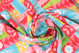 Swirled swatch patchwork fabric (red, pink, blue, green, yellow rectangular and square small patches allover containing small floral graphics in white and same colourway)