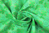 Swirled swatch Clover Swirls fabric (green fabric with tossed green shamrocks outlined with gold sparkles and tossed thin black swirls)