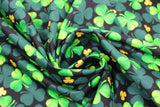 Swirled swatch Clover Toss fabric (black fabric with large and small tossed green clovers in foreground and background in various sizes and shades of green)