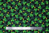 Flat swatch Clover Toss fabric (black fabric with large and small tossed green clovers in foreground and background in various sizes and shades of green)