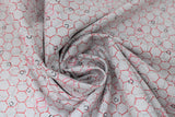 Swirled swatch honeycomb fabric (white fabric with subtle grey honeycomb effect in background medium sized and small red honeycomb pattern on top with tossed pink and black small hexagons)