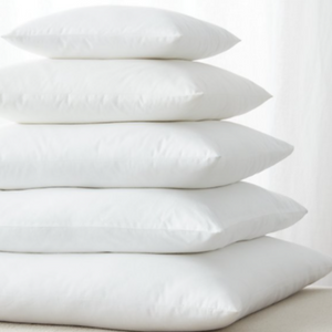 A stack of square, white cushions in decreasing sizes, each centred on the one below it.