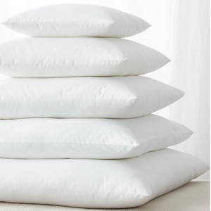 A stack of square, white cushions in decreasing sizes, each centred on the one below it.