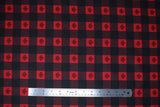 Flat swatch Canada leaf plaid fabric (black, red, and black with red stripes squares allover to create plaid pattern with dark grey maple leaves within red squares)