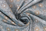 Swirled swatch blue fabric (pale blue/green fabric with floral heads and leafy greenery shapes allover in orange, brown, blue floral heads, and dark blue greenery)