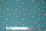 Flat swatch shrooms fabric (teal fabric with tiny faint white polka dots allover and tossed white mushrooms with dark grey/black stems and spots)