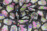 Swirled swatch small black sugar skulls fabric (black fabric with small tossed white and multi-coloured sugar skulls allover with tossed colourful floral)