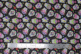 Flat swatch small black sugar skulls fabric (black fabric with small tossed white and multi-coloured sugar skulls allover with tossed colourful floral)