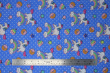 Flat swatch blue unicorns & donuts fabric (medium blue fabric with small white polka dots and tossed cartoon white unicorns with rainbow main and pink bangs/tails, tossed cartoon rainbows with smiling clouds, tossed brown donuts half dipped in pink with sprinkles, tossed stars)