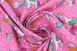 Swirled swatch pink unicorns & donuts fabric (bubblegum pink fabric with small white polka dots and tossed cartoon white unicorns with rainbow main and pink bangs/tails, tossed cartoon rainbows with smiling clouds, tossed brown donuts half dipped in pink with sprinkles, tossed stars)