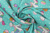 Swirled swatch green unicorns & donuts fabric (teal green fabric with small white polka dots and tossed cartoon white unicorns with rainbow main and pink bangs/tails, tossed cartoon rainbows with smiling clouds, tossed brown donuts half dipped in pink with sprinkles, tossed stars)